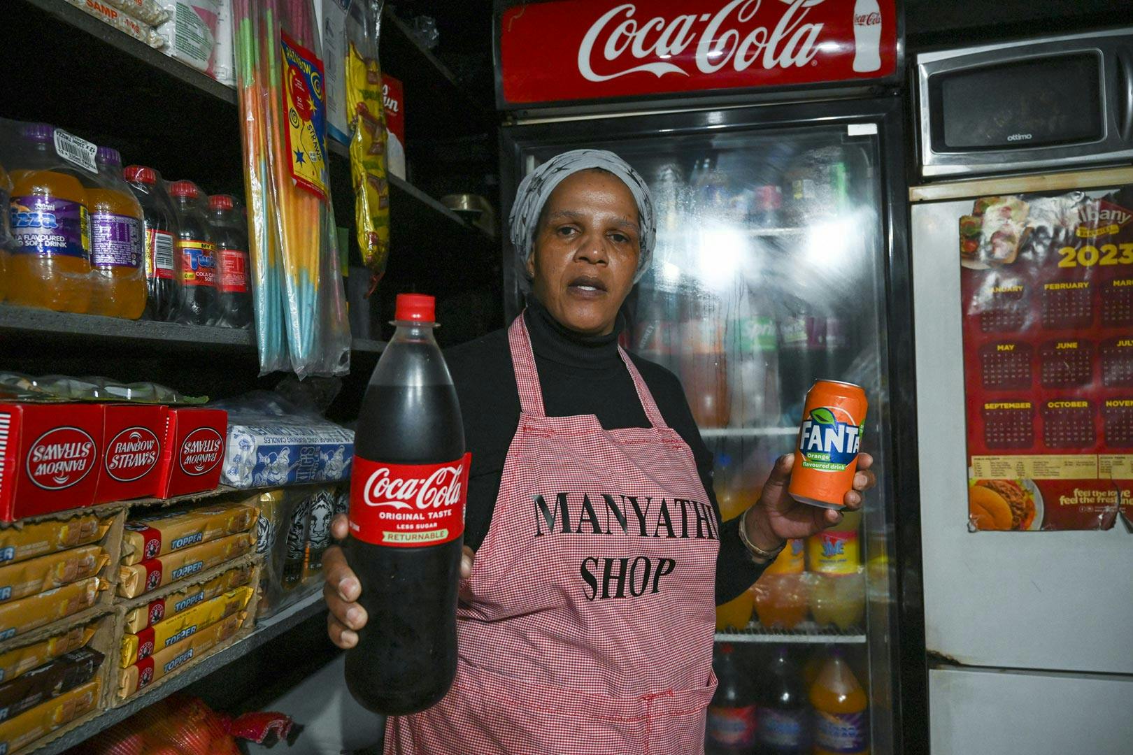 A woman with Coca-Cola products in her small store in a shipping container in Cape Town