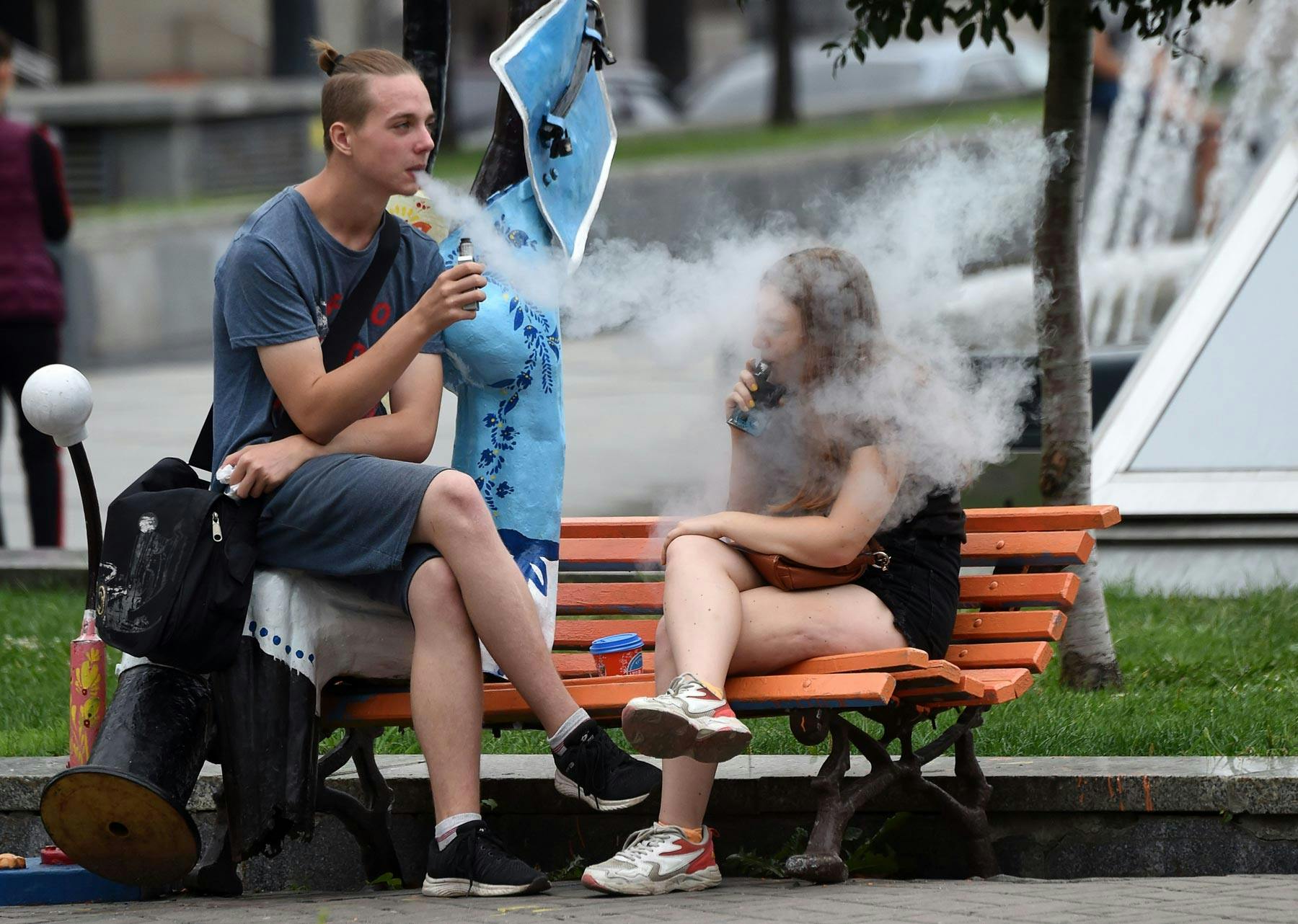 Young people smoke electronic cigarettes as they rest in the Ukrainian capital of Kiev, in 2019.
