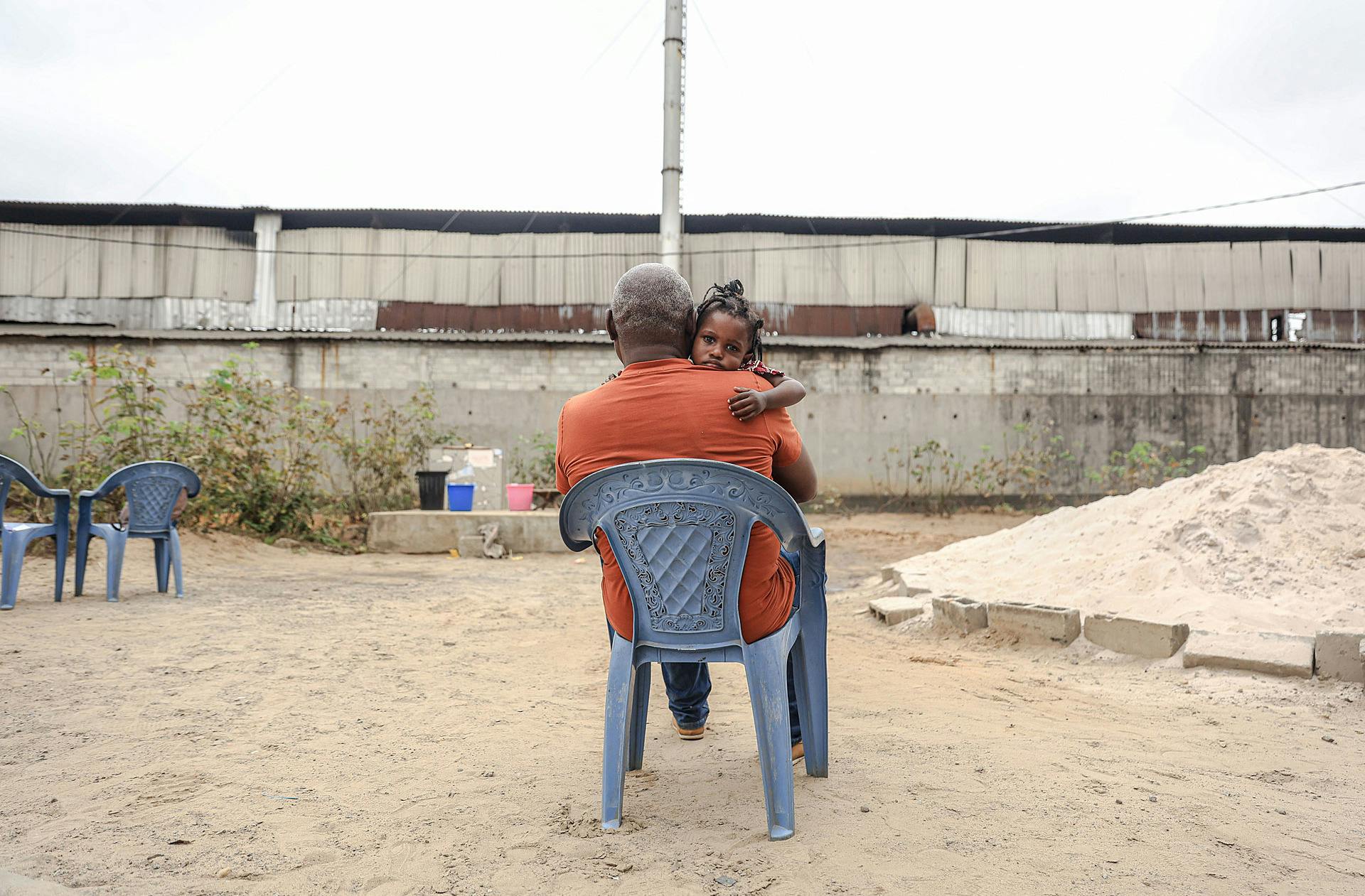A man cradles his daughter in his yard, near the METSSA Congo factory in Vindoulou