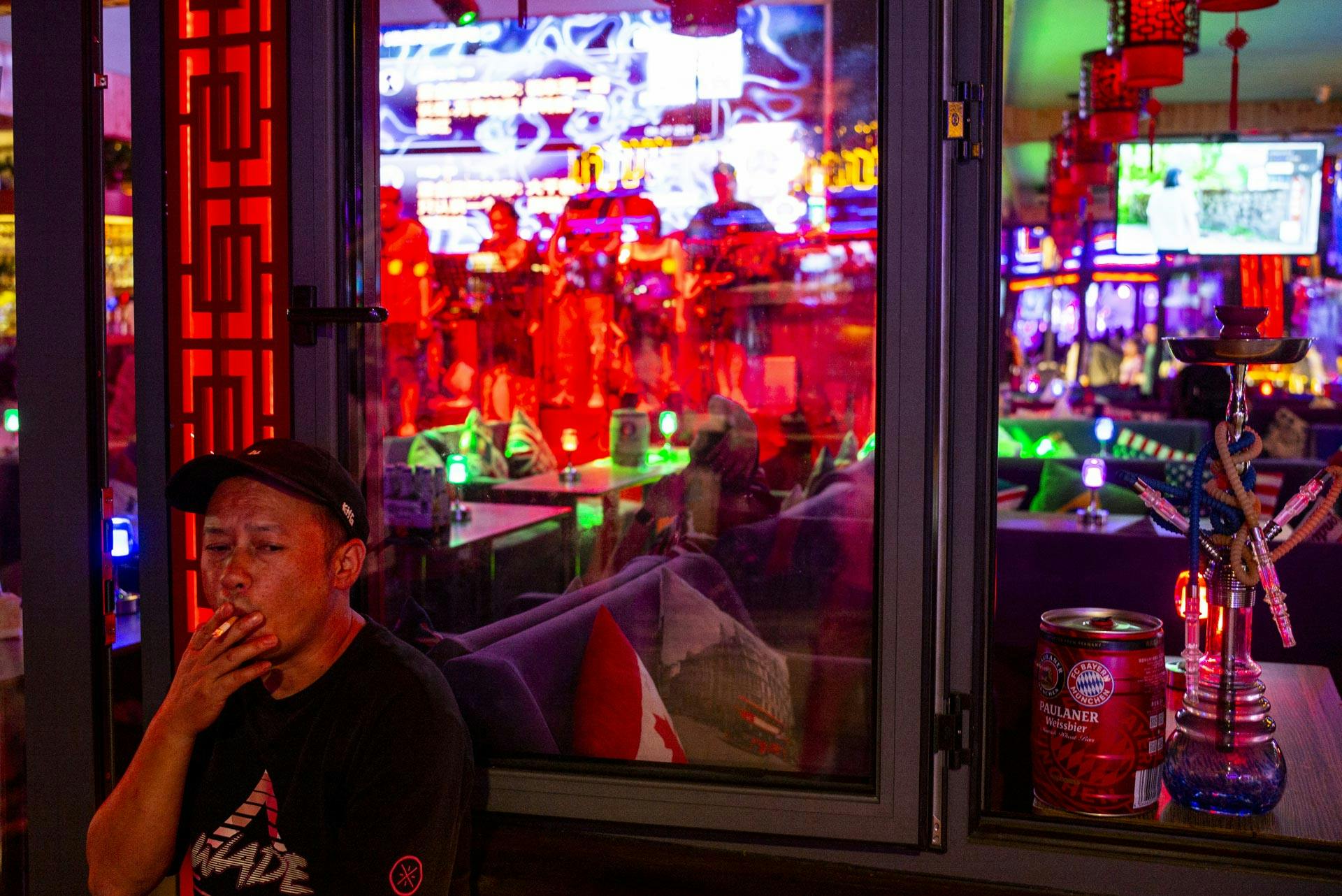 A man smokes a cigarette in the Shizahai bar area in Beijing, China